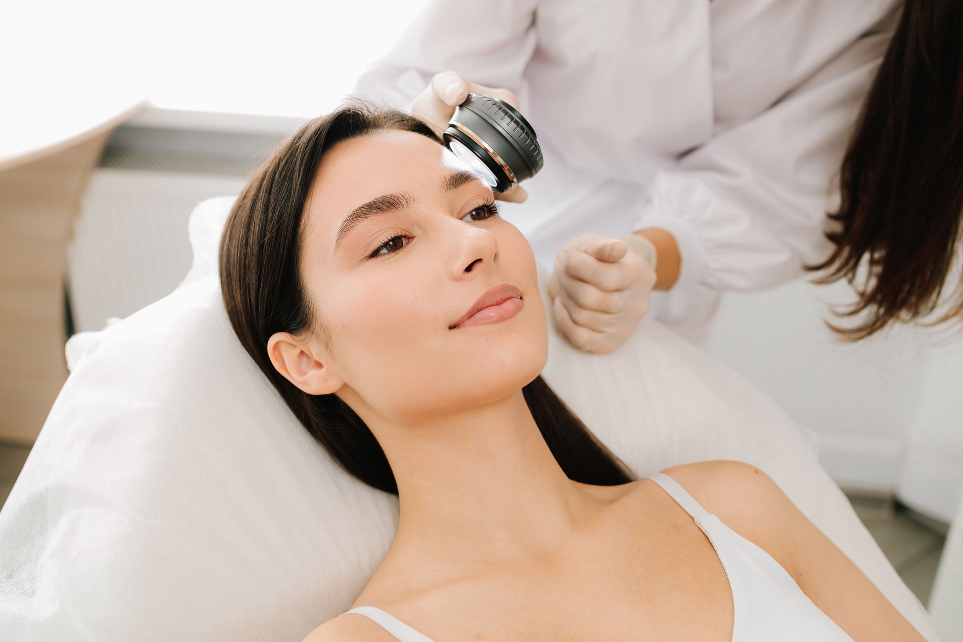 Woman receiving facial treatment with a handheld device in a spa setting