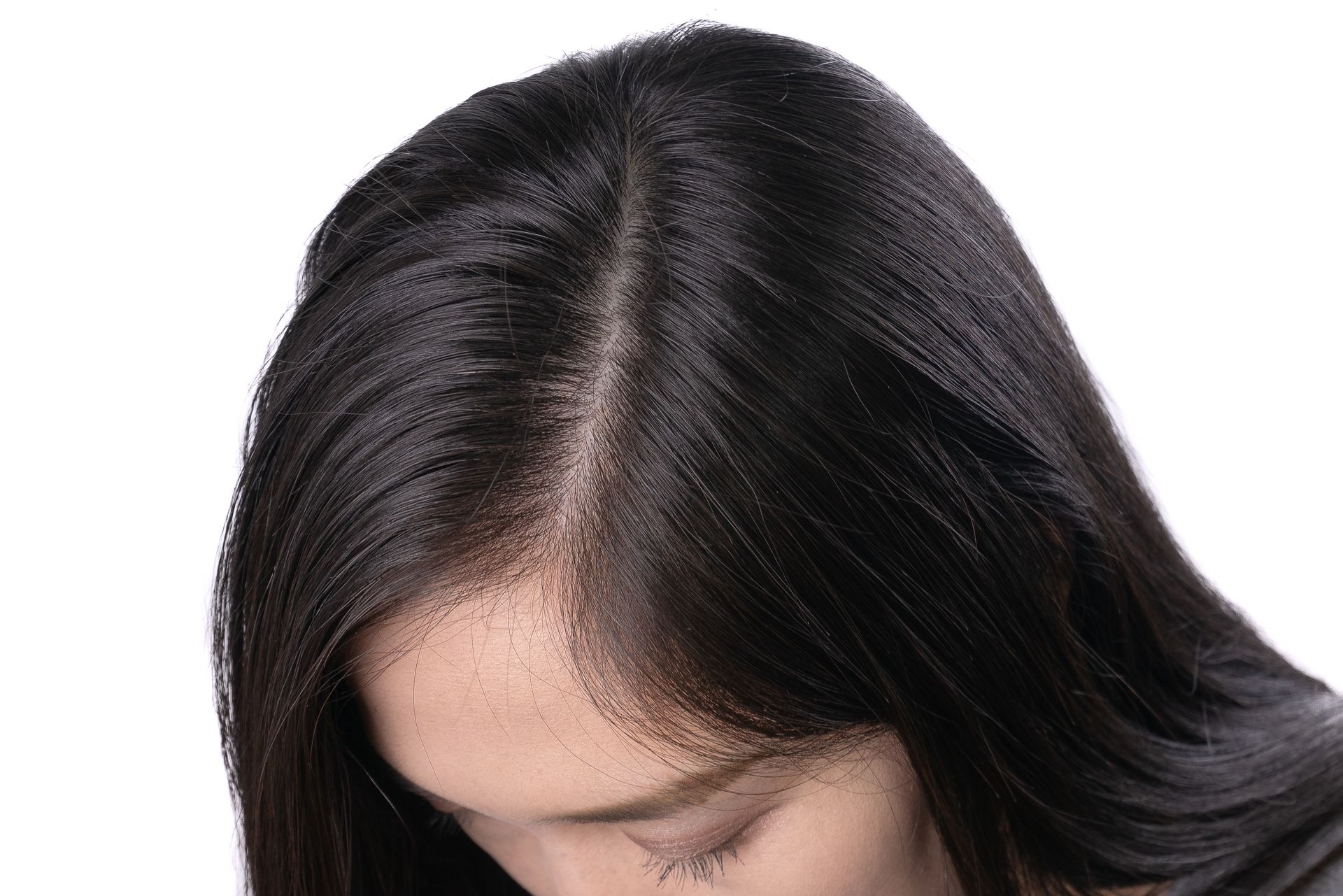 A woman with long black hair is looking down at her hair.
