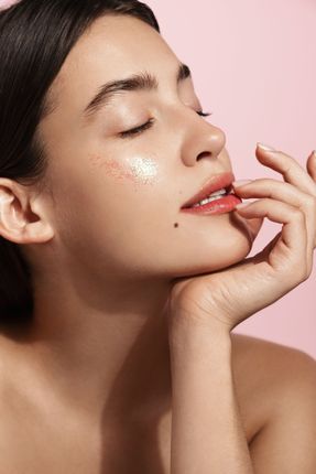 A close up of a woman 's face with her eyes closed and her hand on her chin.