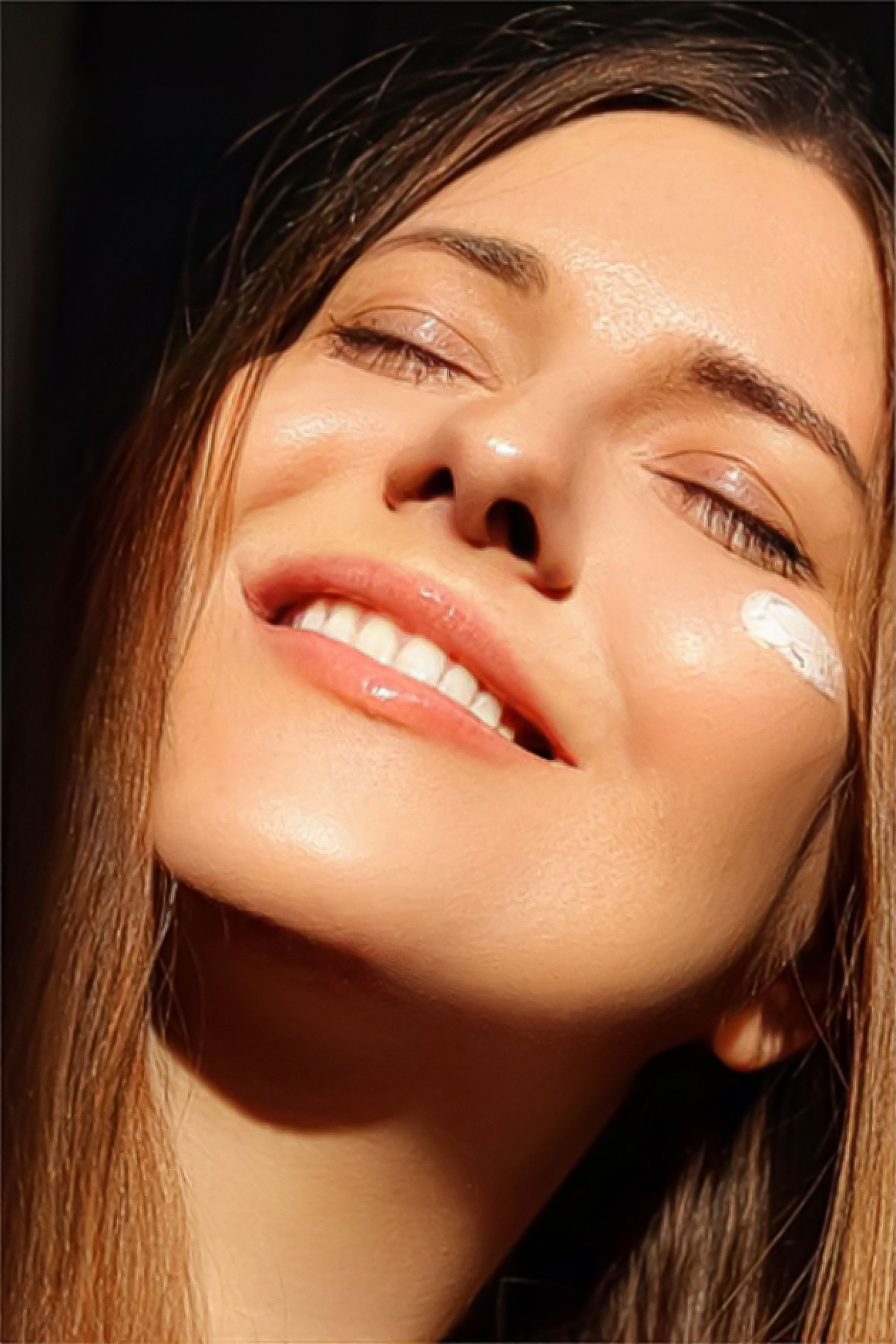 A close up of a woman 's face with a cream on her face.