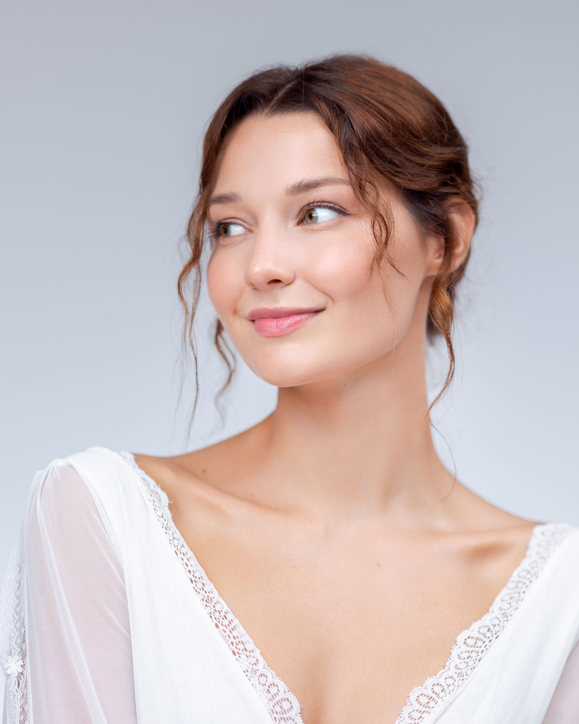Woman with light brown hair, smiling, wearing a white dress.