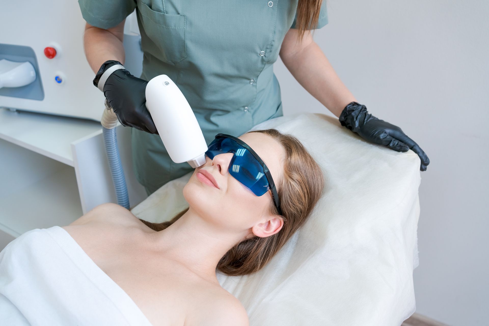 Woman wearing protective eyewear receiving laser facial treatment.