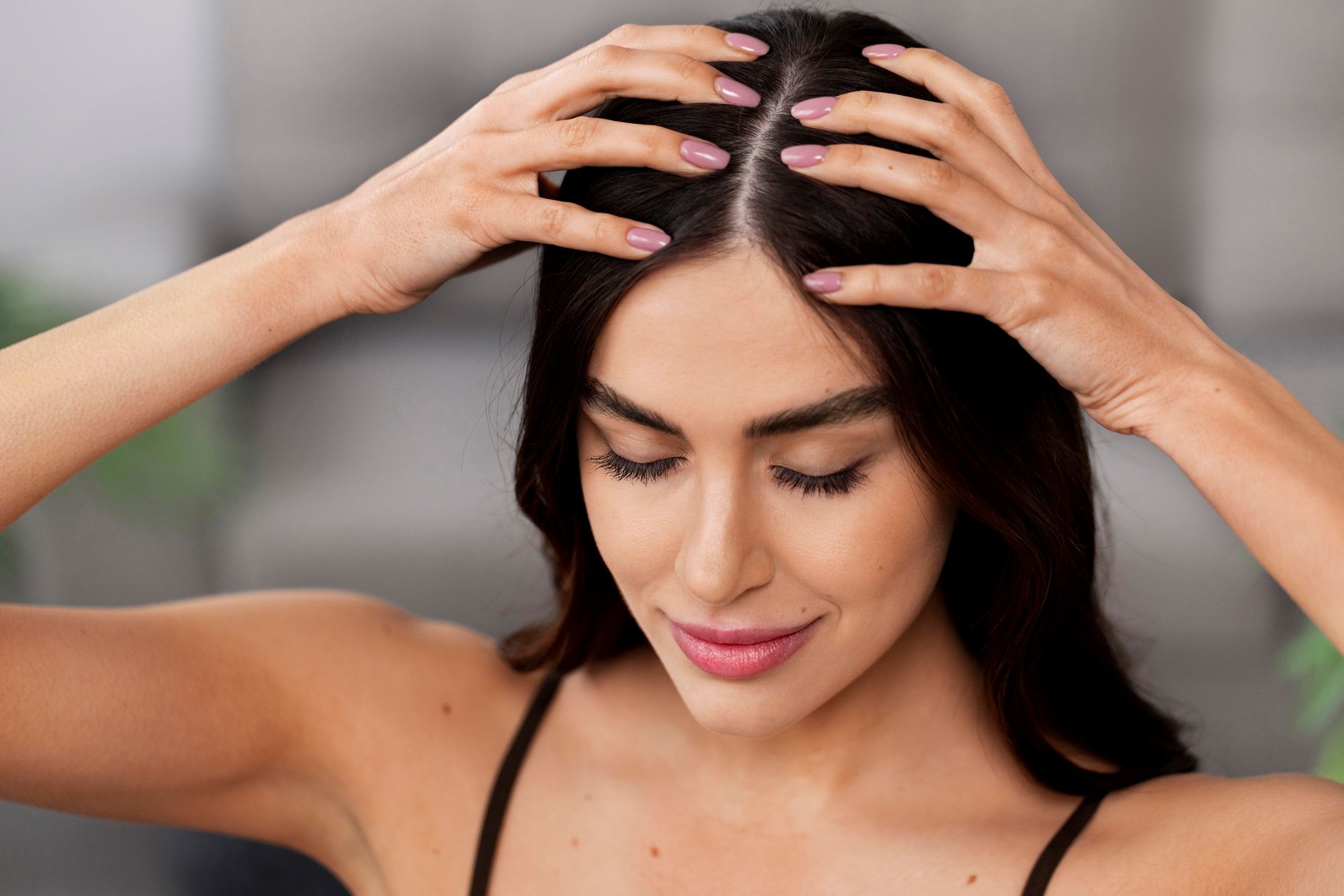 A woman is massaging her head with her hands.