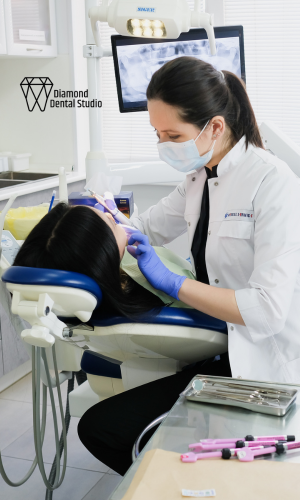 A dentist is examining a patient 's teeth in a dental studio.