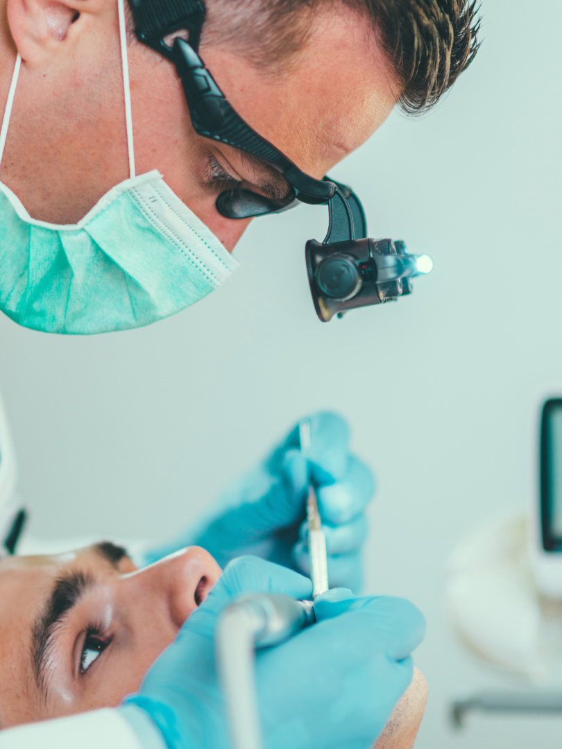 A dentist is examining a patient 's teeth in a dental studio.