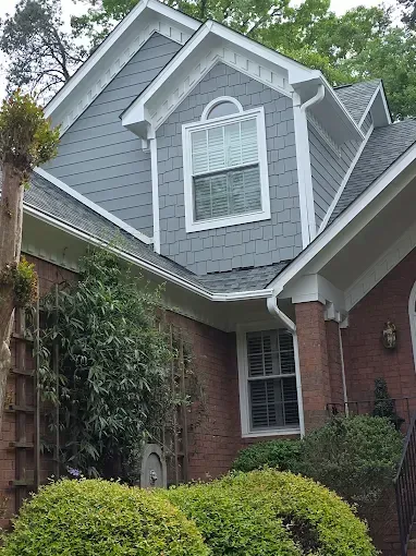 Brick house with gray siding, white trim, and a gabled roof.