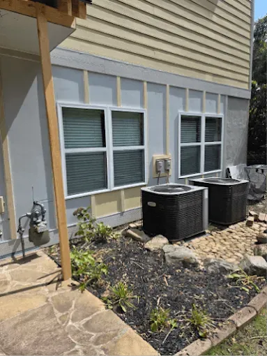 Exterior house view with windows, air conditioners, and landscaping. Construction work in progress.