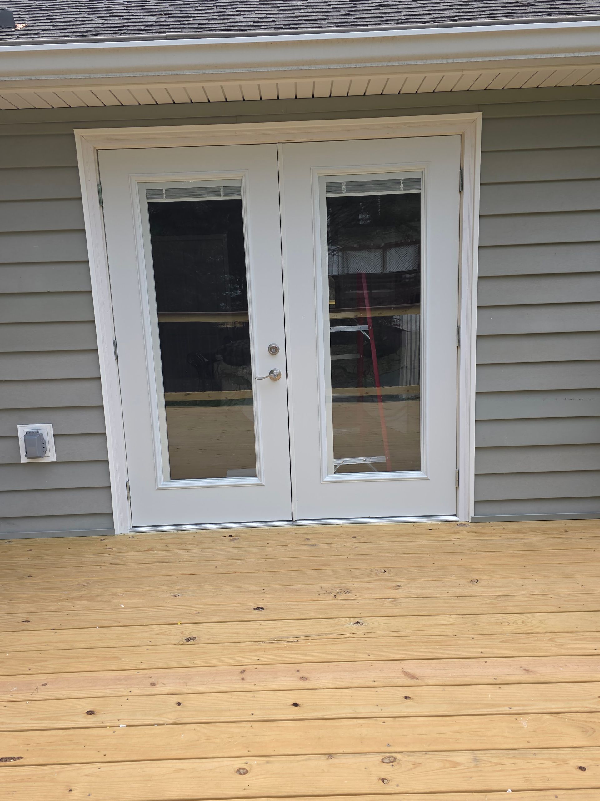 Hand opening a silver door handle on a white door.