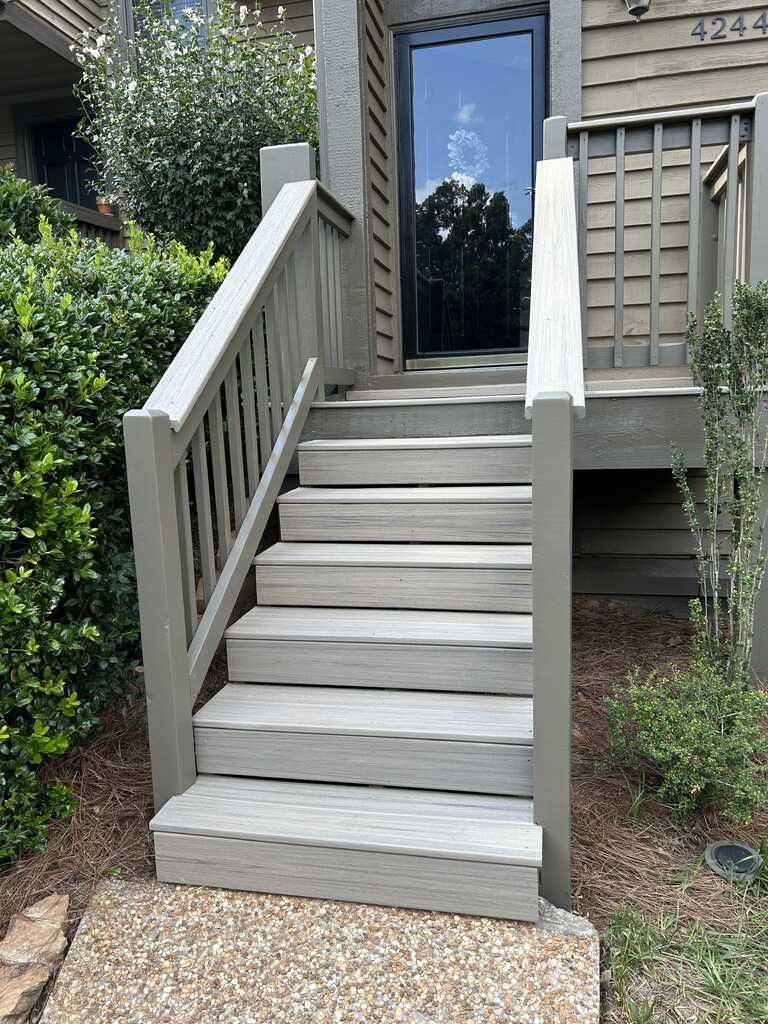 Gray wooden staircase leading up to a front door of a building.