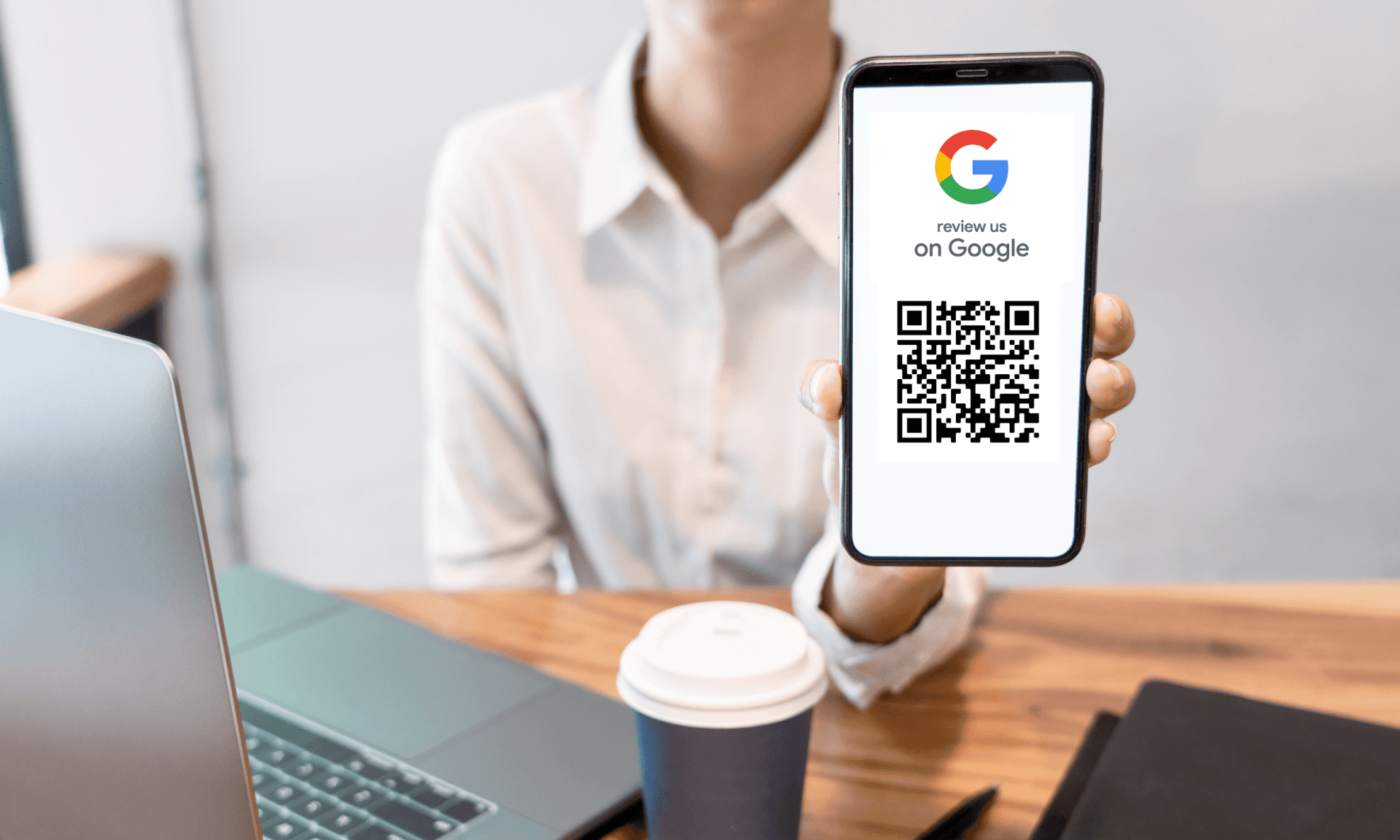 Person holding up their cell phone with a Submit a Google Review QR code