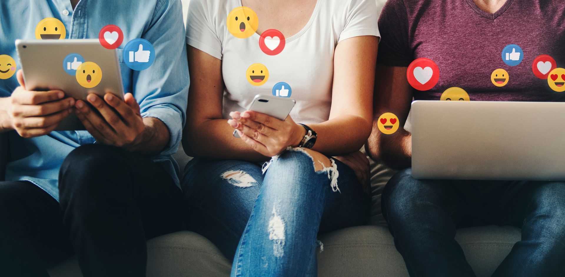 Three individuals sitting down looking at social media with emojis coming out of their phone, tablet