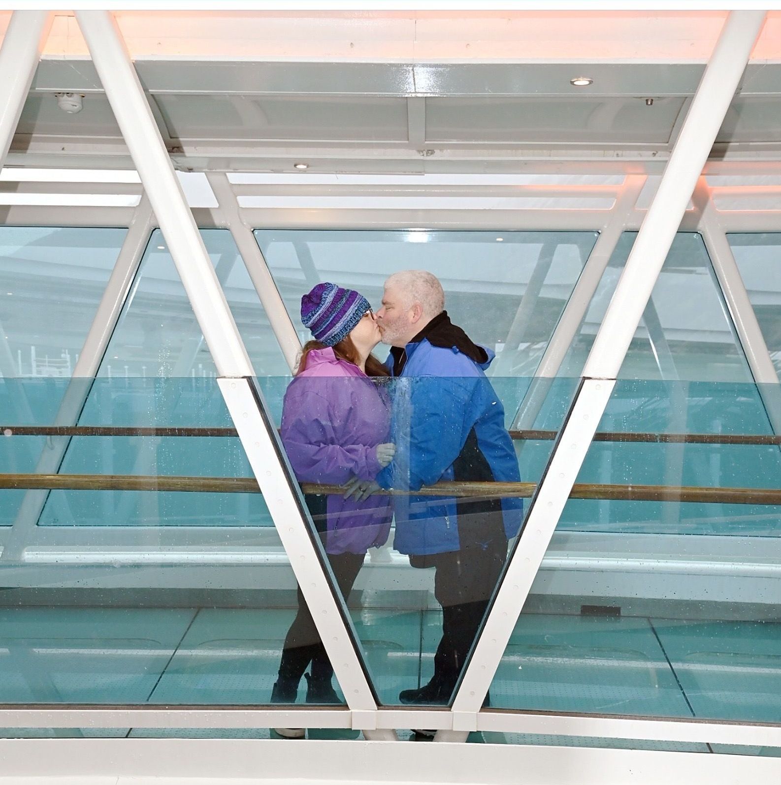 A man and a woman are kissing on a bridge