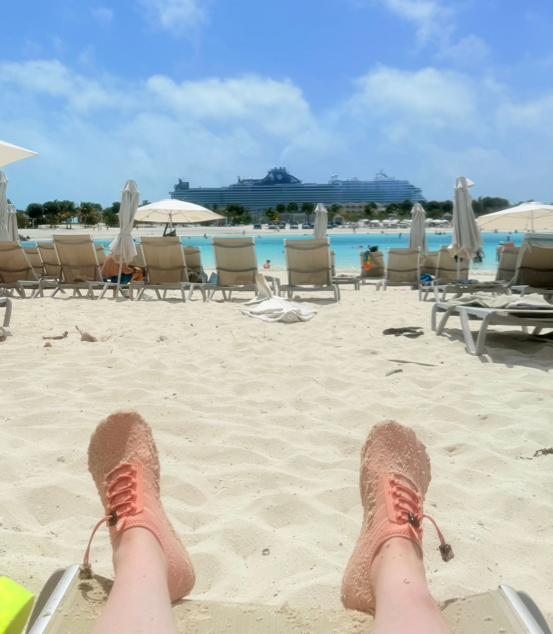 A person laying on a beach with a boat in the background
