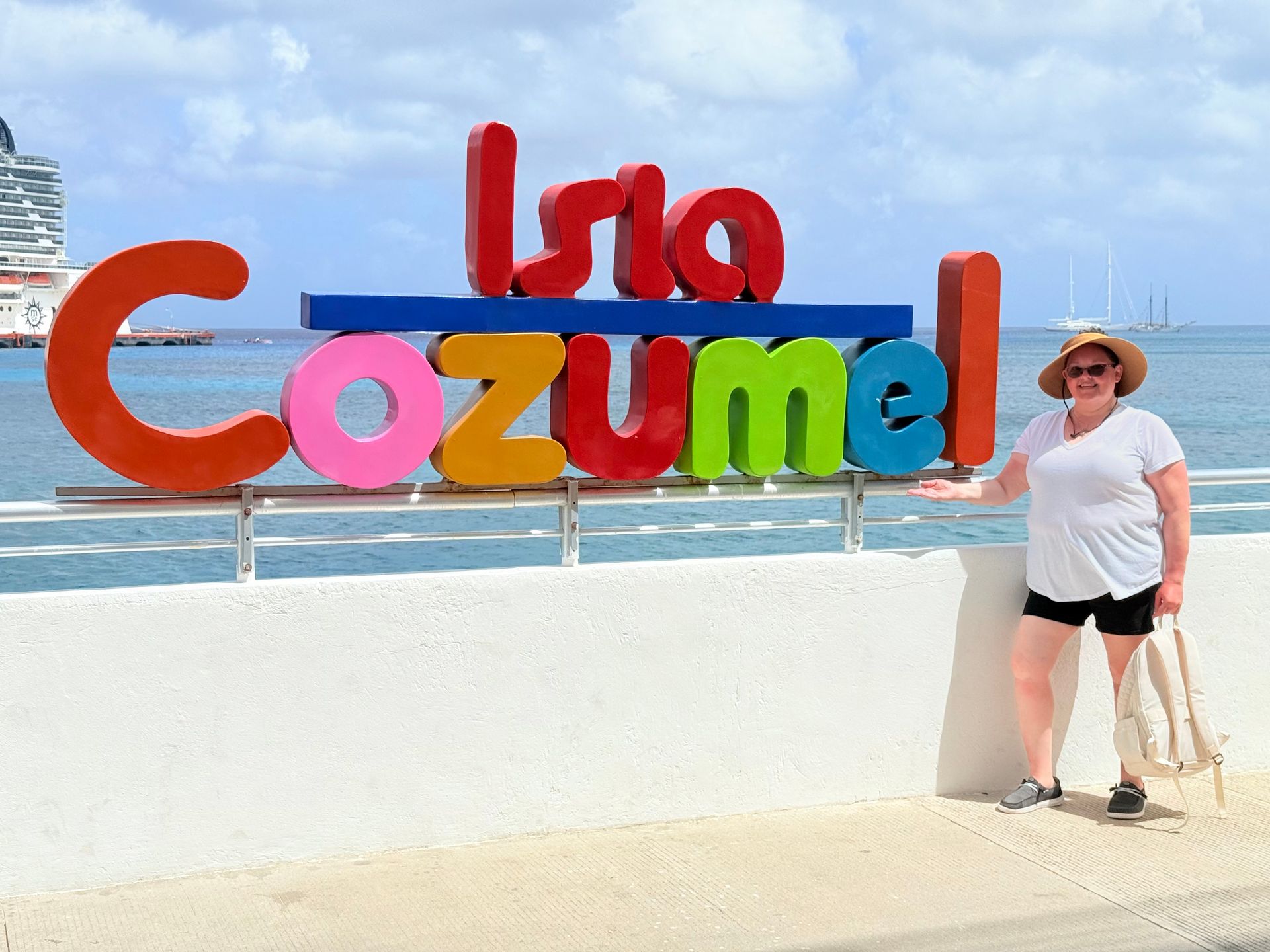 A woman is standing in front of a sign that says isla cozumel
