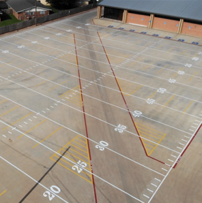 Aerial view of a concrete football field with white and red lines.