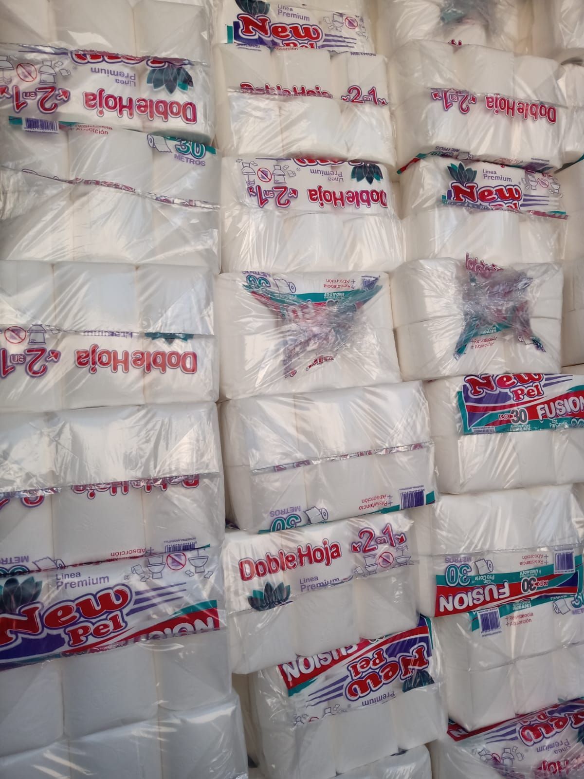 Una pila de paquetes de papel higiénico de la marca New Pel, envueltos en plástico.