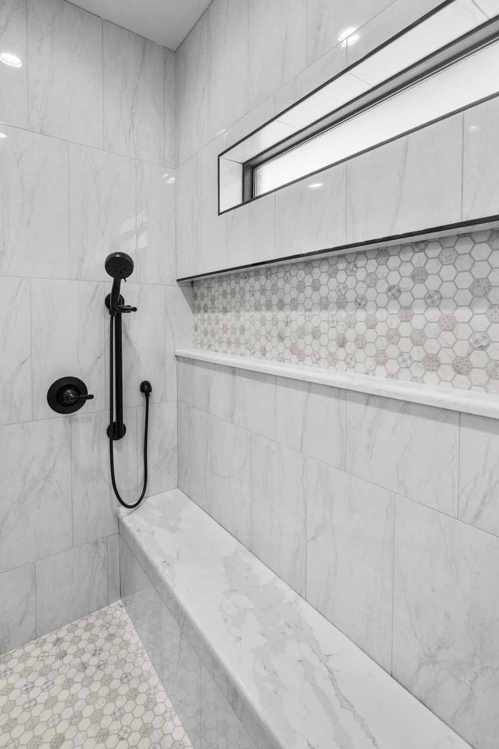 Modern white tiled shower with built-in bench, shelf, and black shower fixtures.