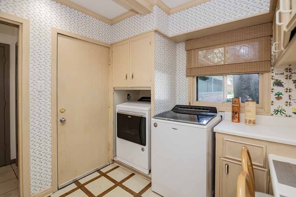 Laundry room with washer, dryer, cabinets, and window with a bamboo shade.
