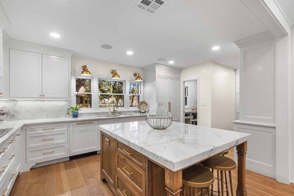 A bright, white kitchen with a wooden island, countertops, and wood flooring.