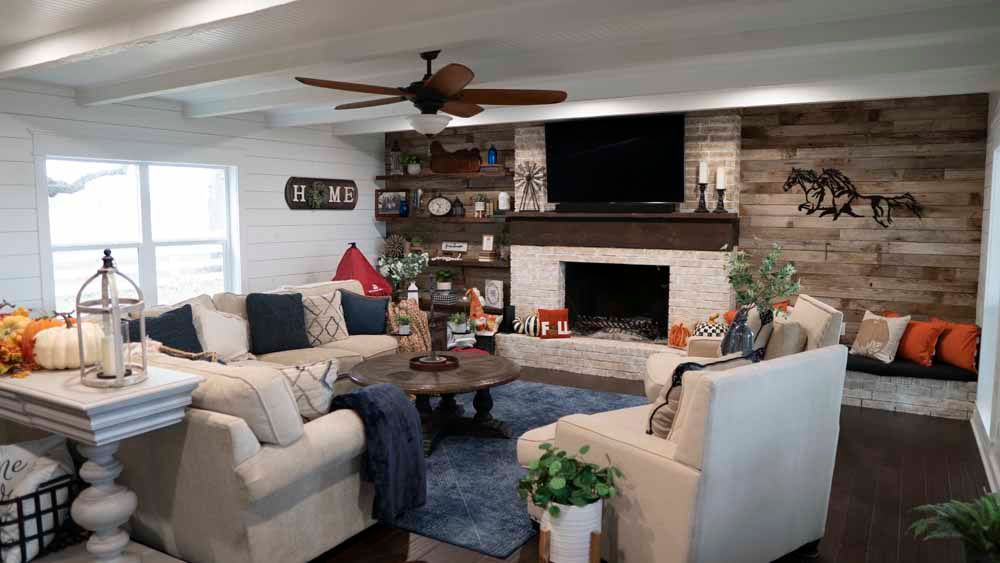 Cozy living room with fireplace, white couches, and wooden accents. Features a mounted TV and seasonal decor.
