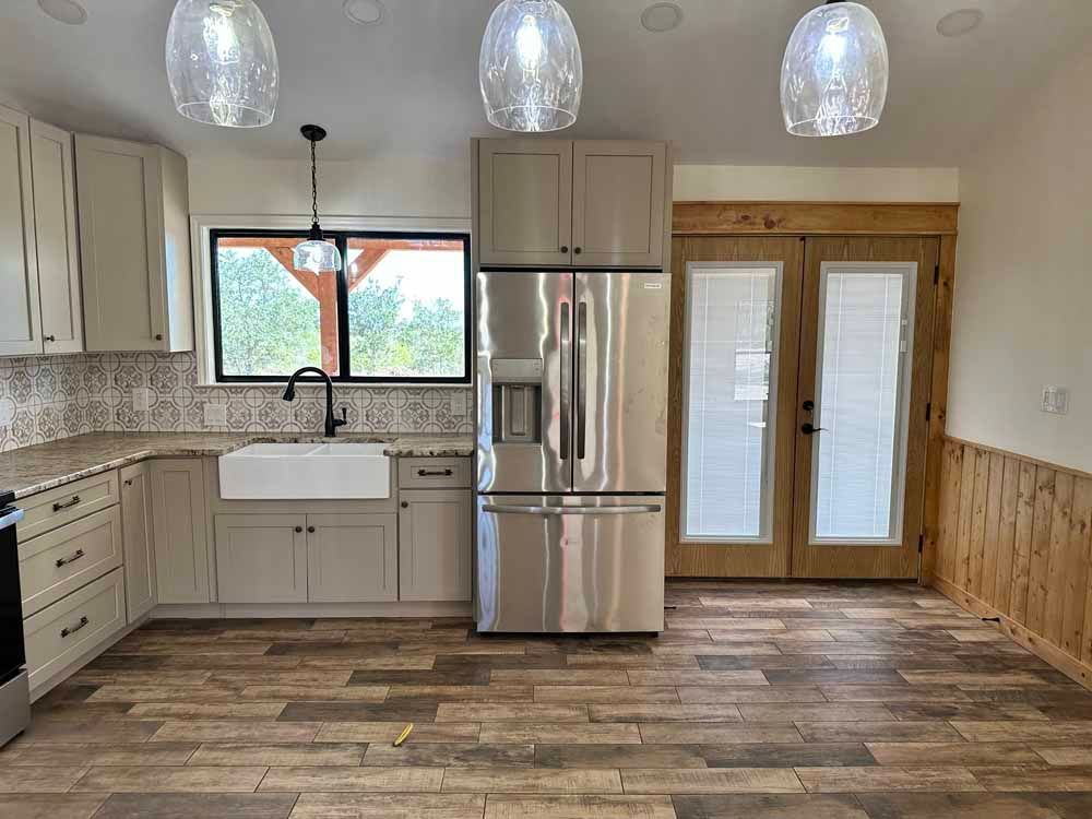 Kitchen with light cabinets, stainless steel refrigerator, farmhouse sink, and wood-look flooring.