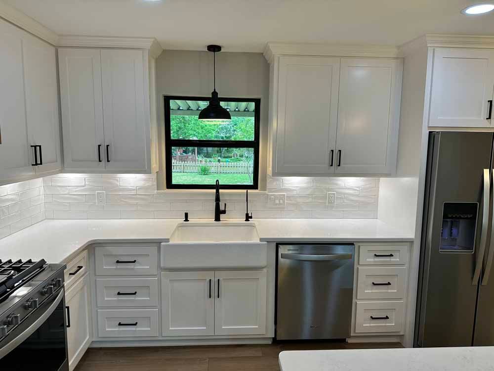 White kitchen with cabinets, a farmhouse sink, stainless steel appliances, and a window with a view.
