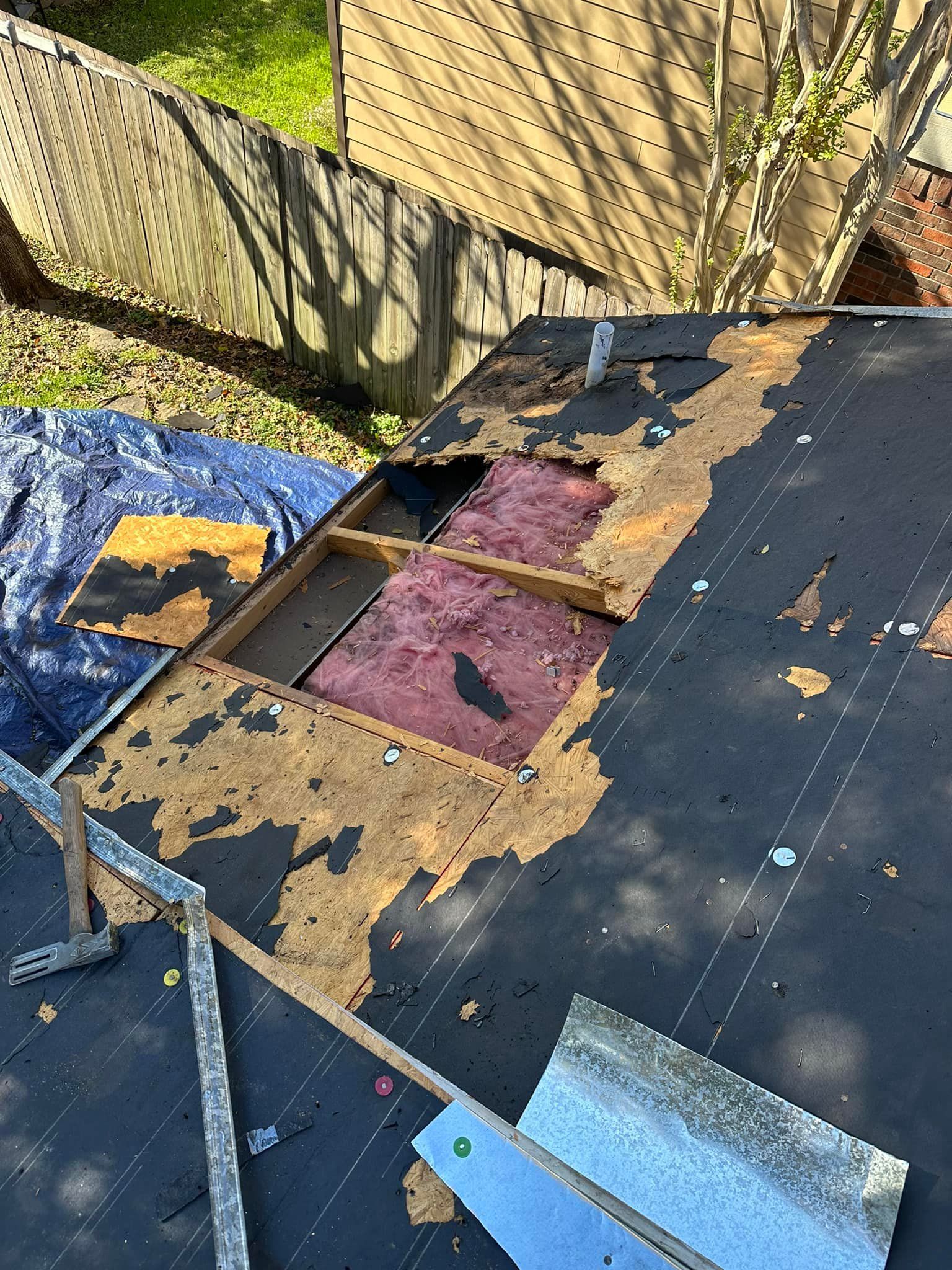 Damaged roof with missing shingles and exposed insulation.