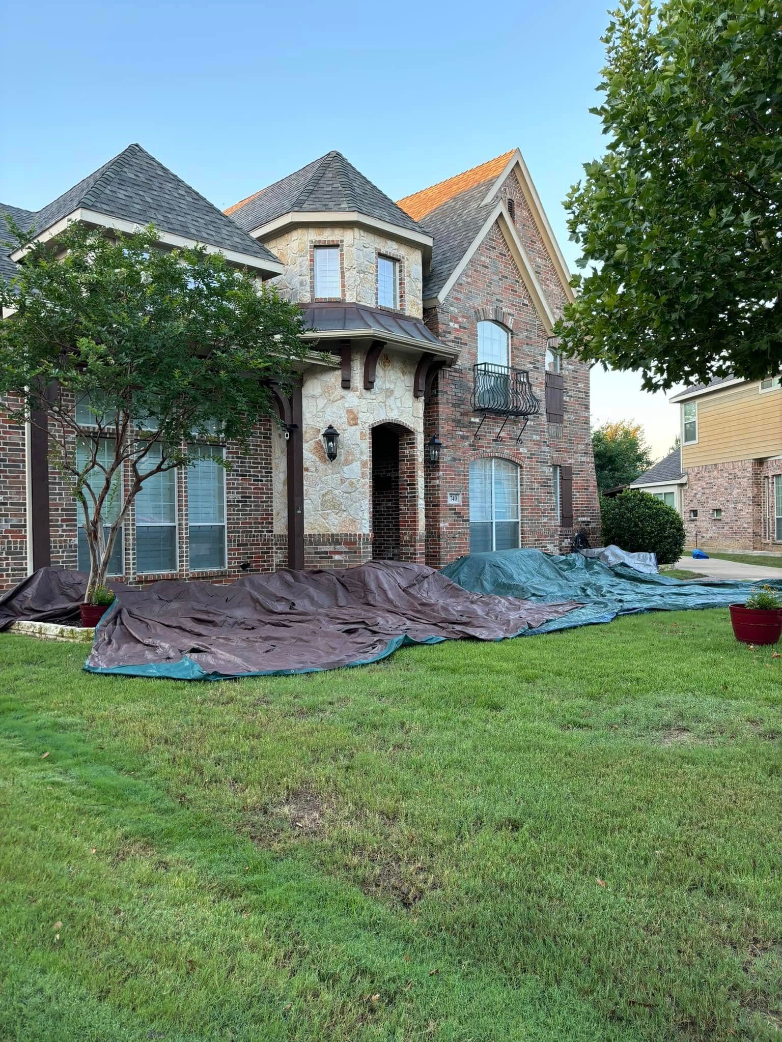 A large house with brown and green tarps covering the grass.