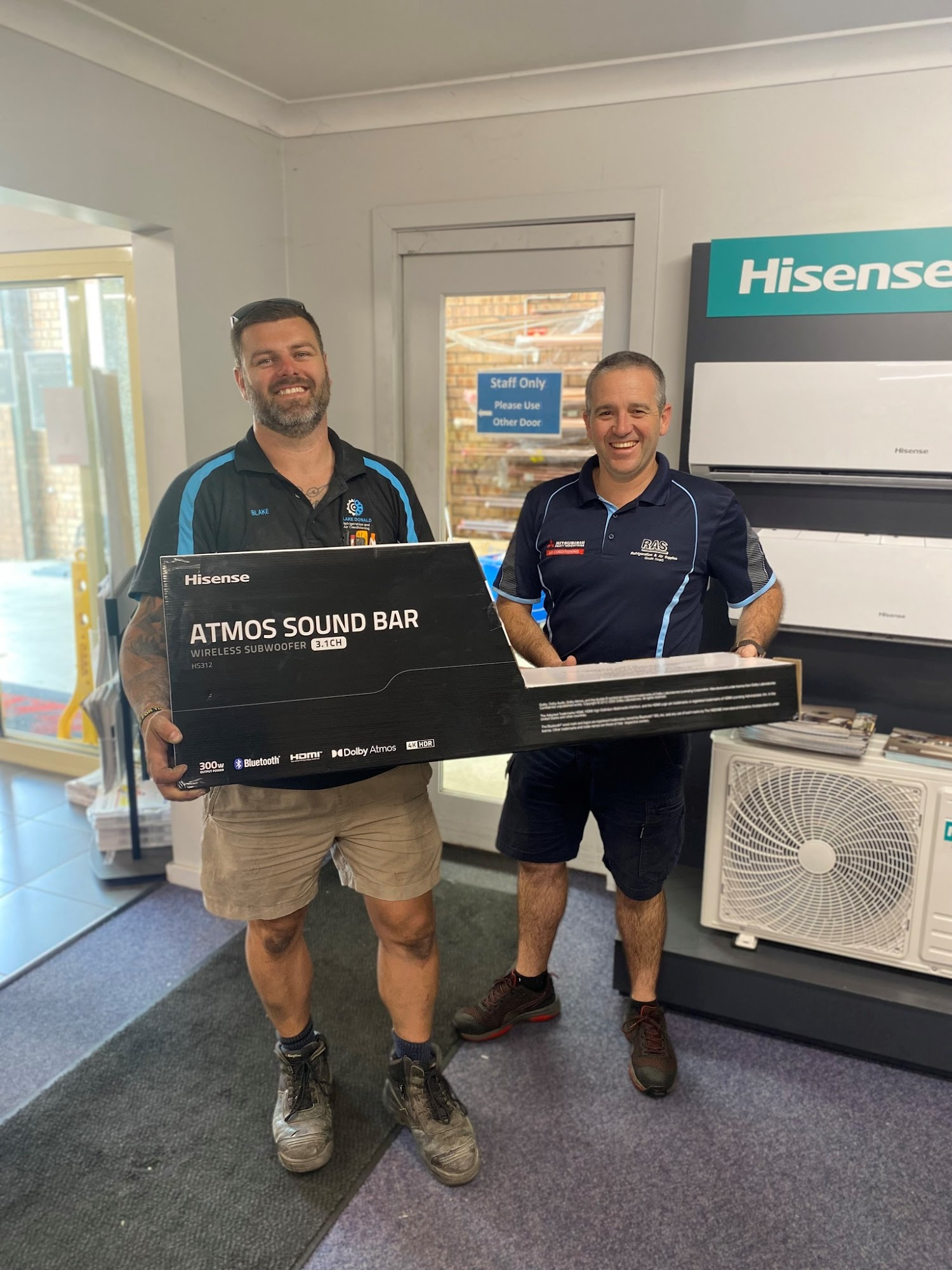 Two Men Holding a Sound Bar Box Inside an Appliance Store — Refrigeration & Air Supplies (South Coast) In Wollongong, NSW
