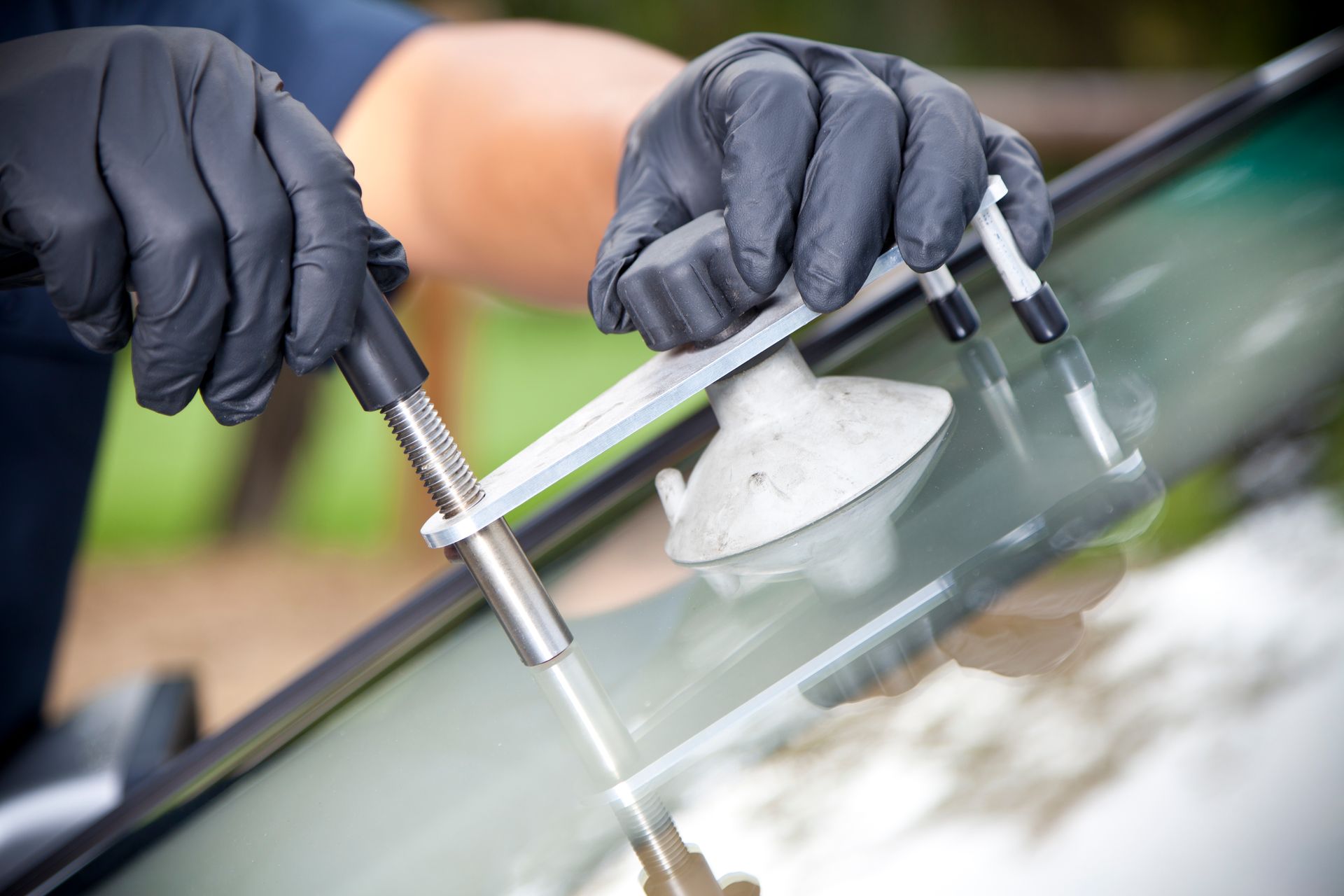 Close-up of hands of mechanic repairing a glass on a car outdoors.