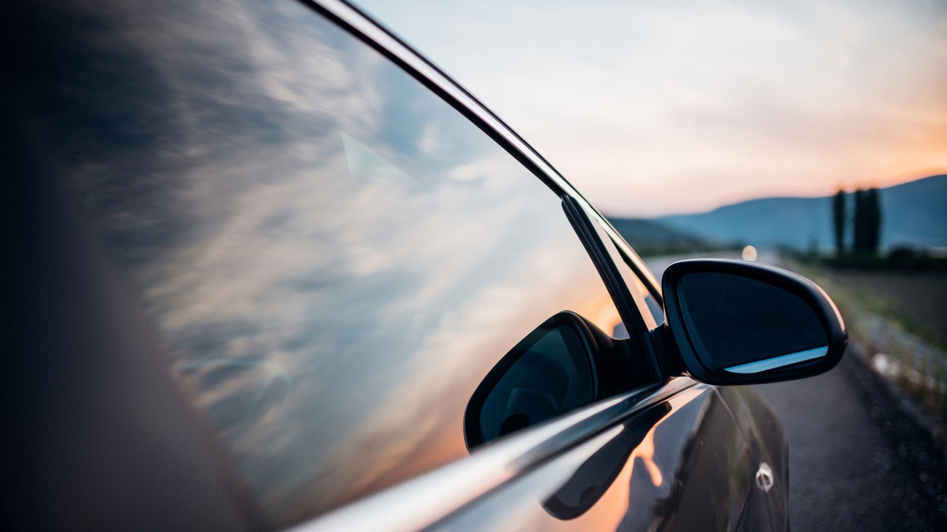 A car is parked on the side of the road at sunset.