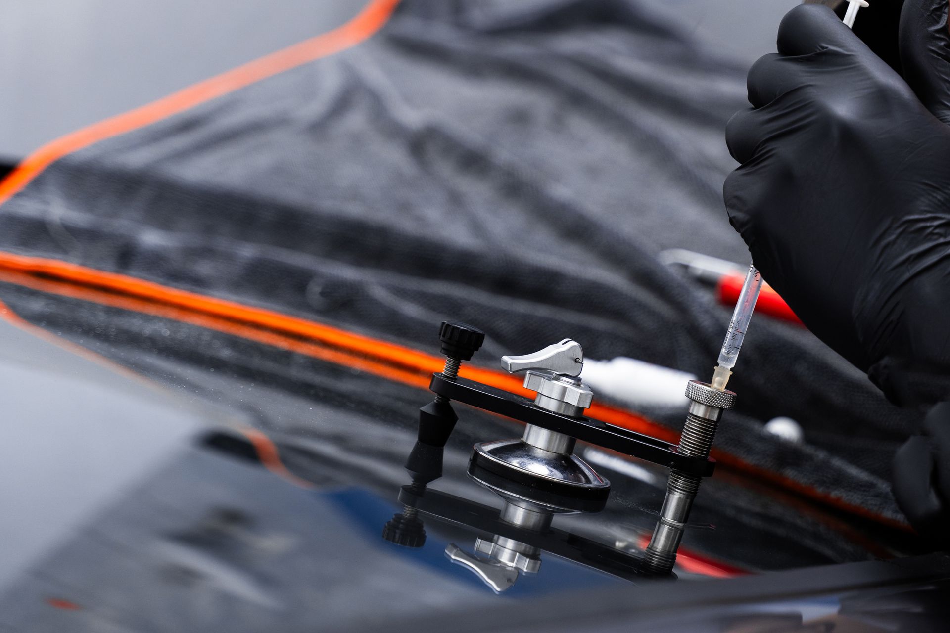 Technician working on a resin repair on windshield using injector application to restore structural clarity. Technician working on a resin repair on windshield using injector application to restore structural clarity.