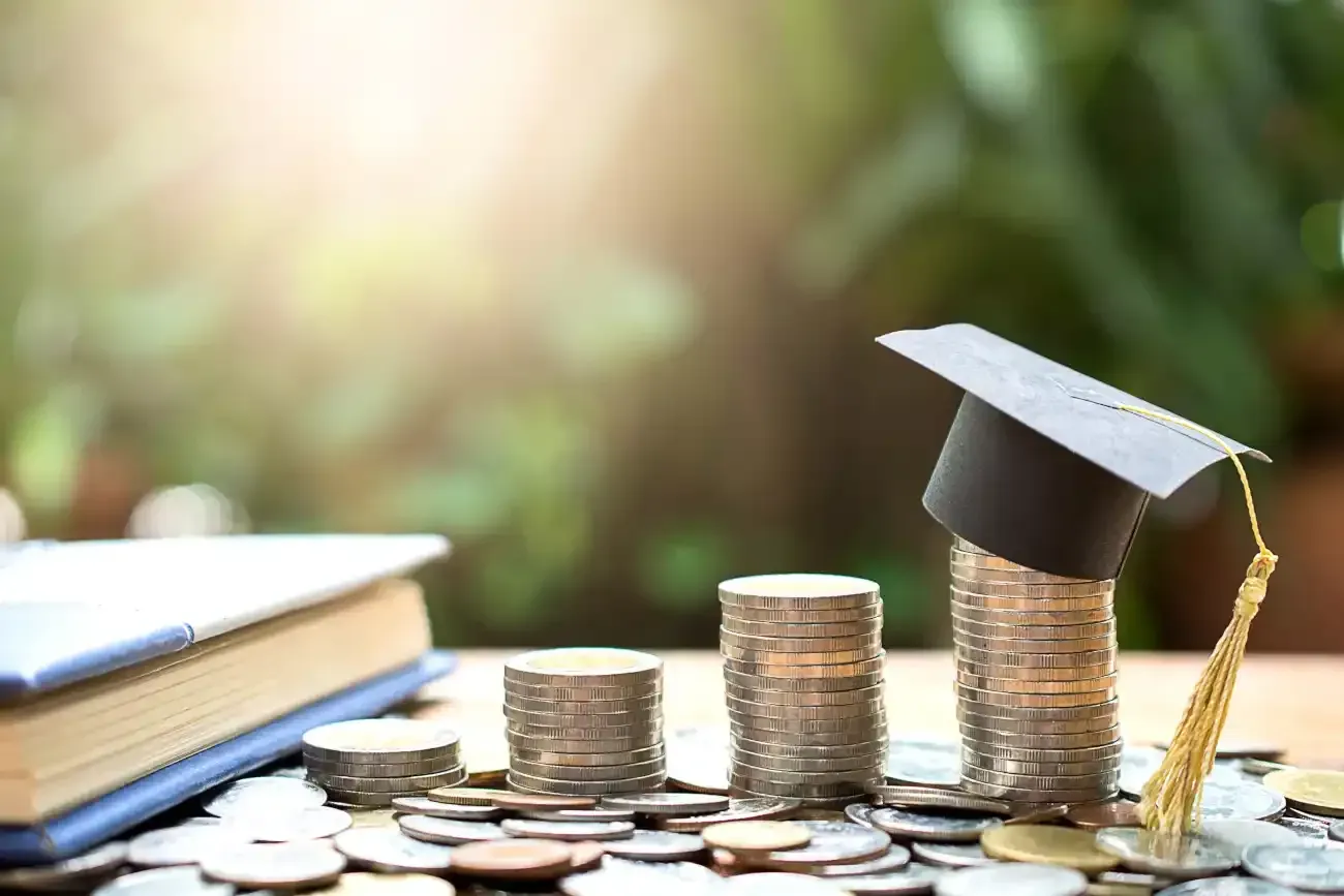 A graduation cap on top of a stack of coins