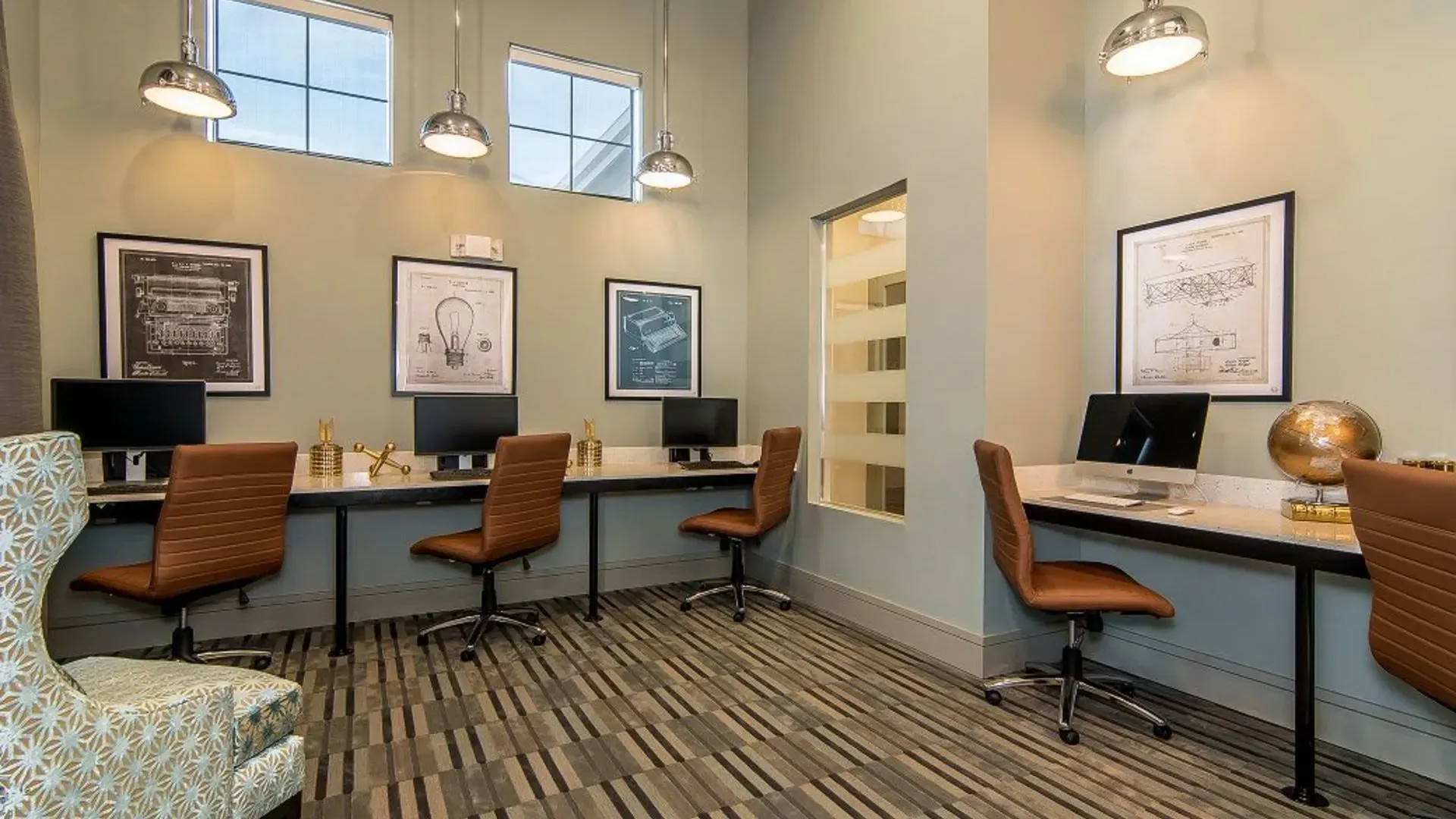 Interior view of a resident community computer center with four workstations and brown chairs.