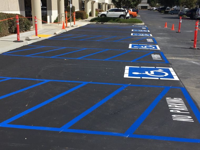 A row of newly painted blue and white accessible parking spaces with striped 