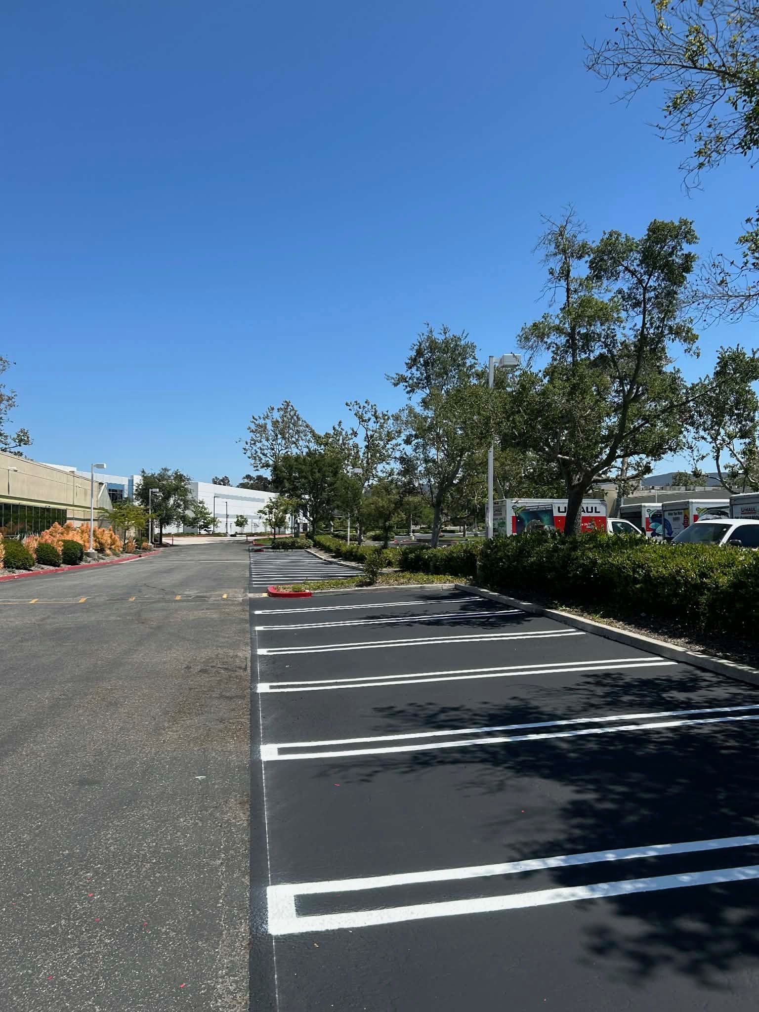 Empty parking lot with parallel parking spaces separated by a white center line and yellow wheel stops.