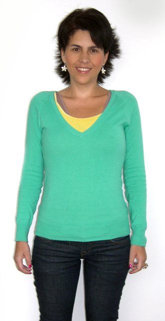 Una mujer lleva un suéter verde y jeans azules.