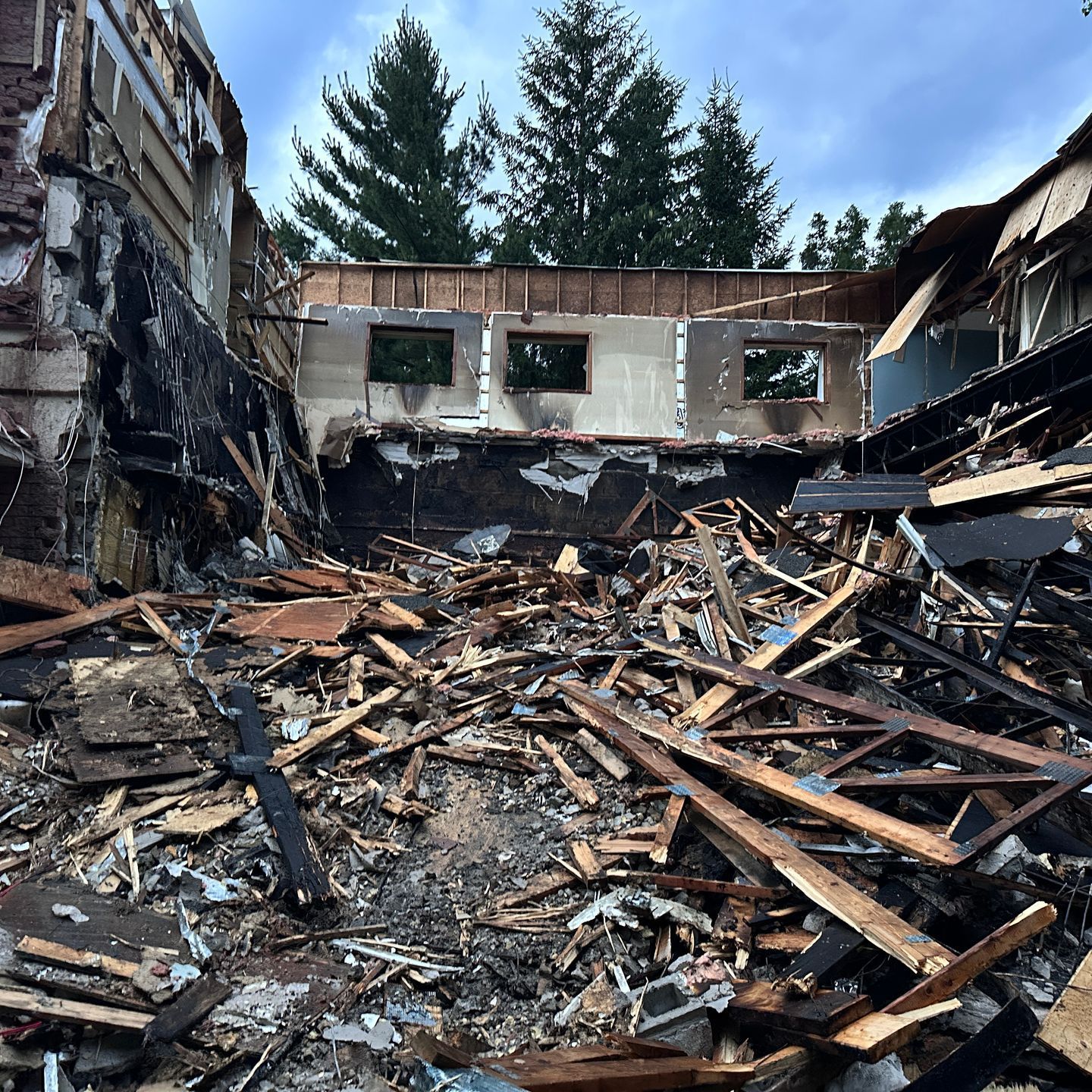 Intérieur rempli de débris après un incendie de structure ; murs carbonisés et vestiges d'un bâtiment.