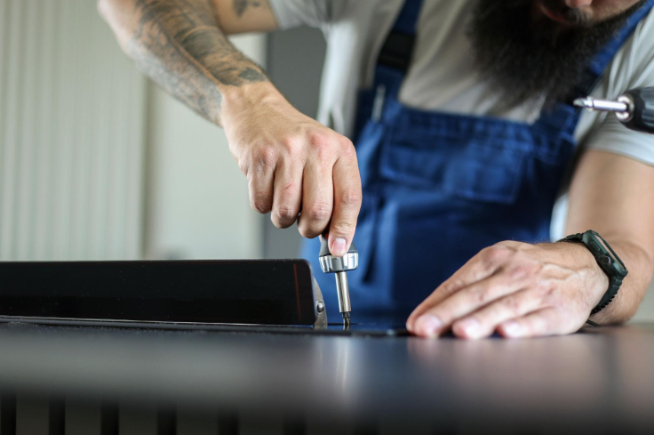 “Close-up of a technician using a screwdriver to inspect and repair a kitchen appliance during an appliance repair service in Millcreek, UT”