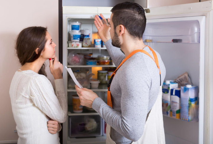 “Technician and homeowner looking inside a refrigerator together during an appliance repair service in Millcreek, UT”