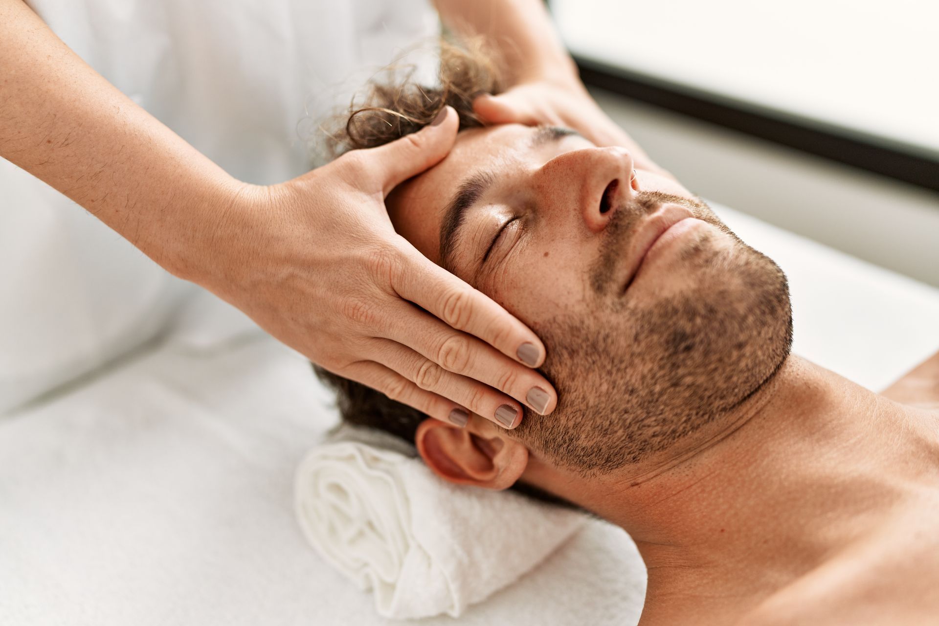 Ein Mann bekommt in einem Spa eine Kopfmassage.