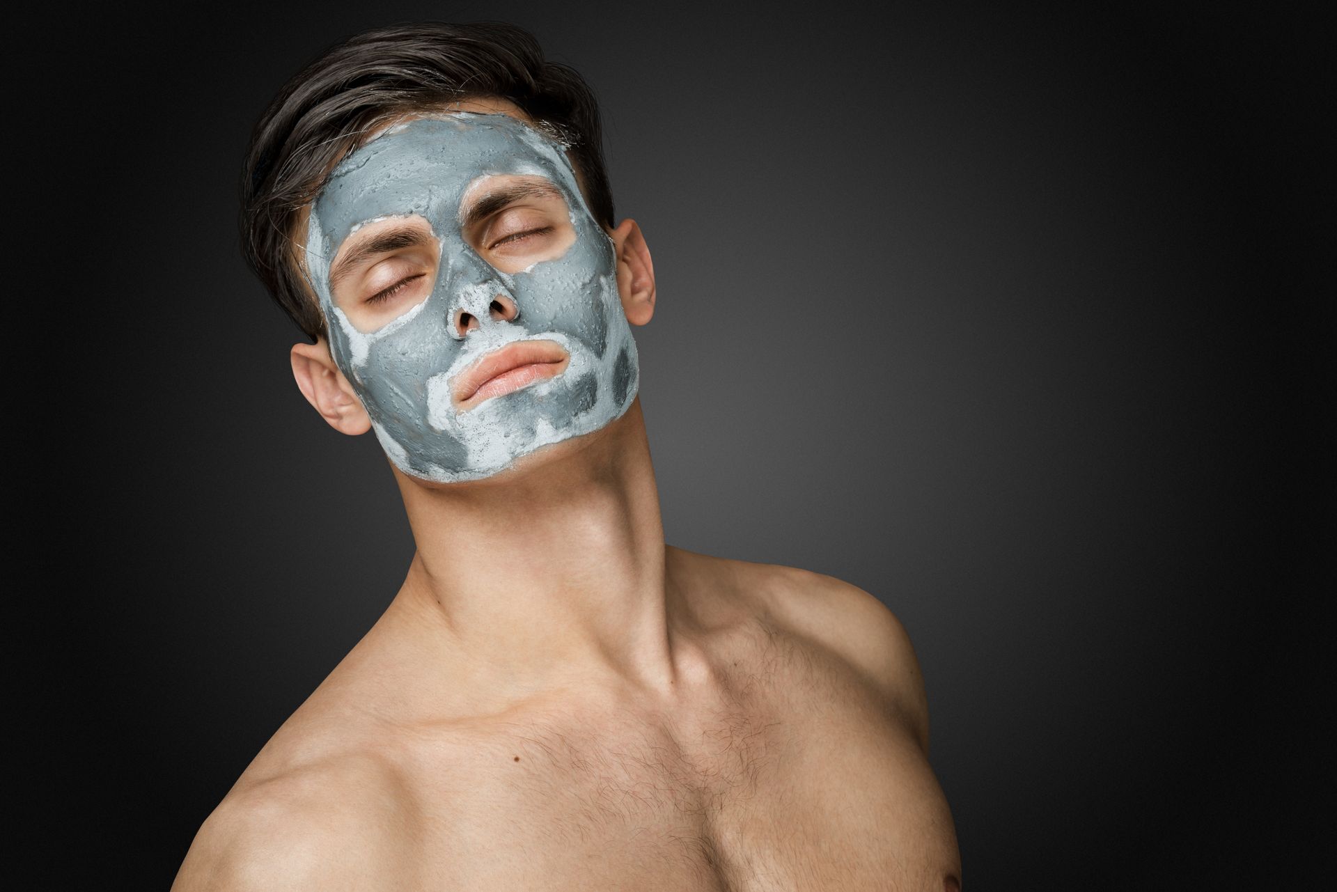 Ein Mann ohne Hemd mit einer Tonmaske im Gesicht.