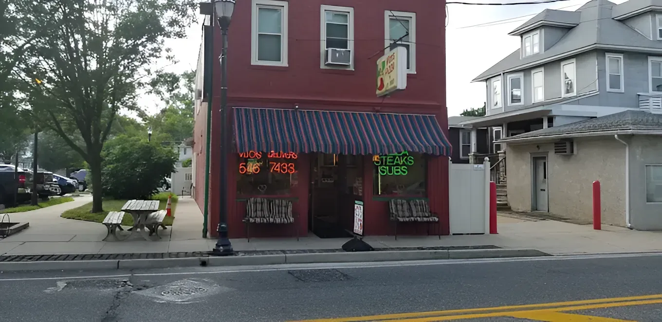 A red building with a blue and white striped awning, a sign, and neon 