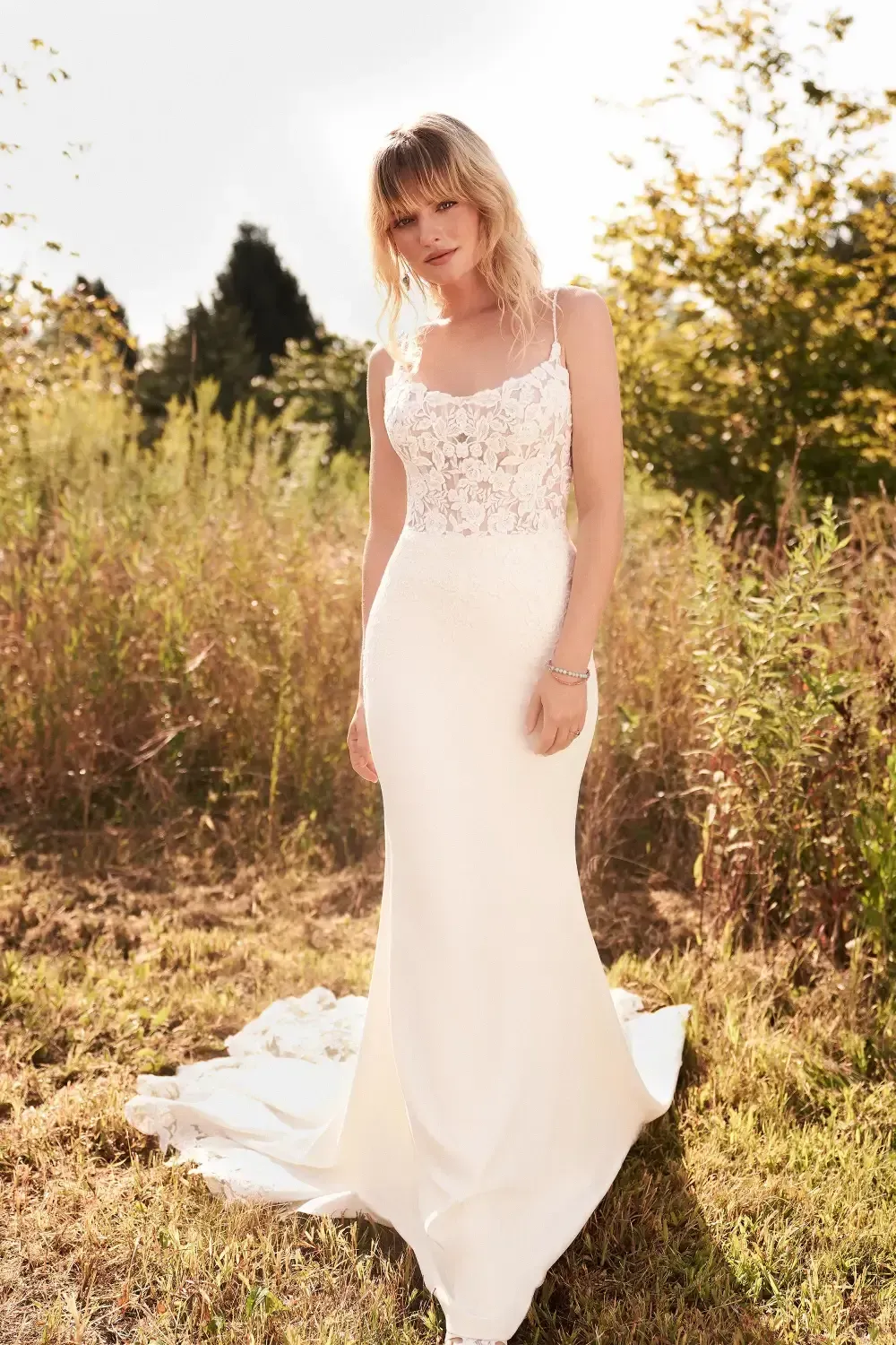 Woman in wedding dress standing outdoors in field.