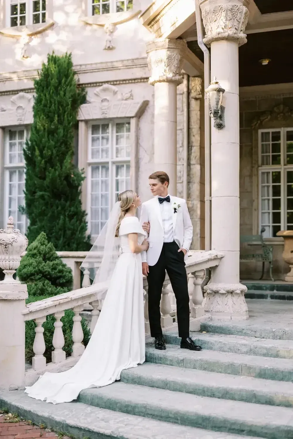A person with brown wavy hair laughs, mouth open, wearing a green shirt, against a white background.
