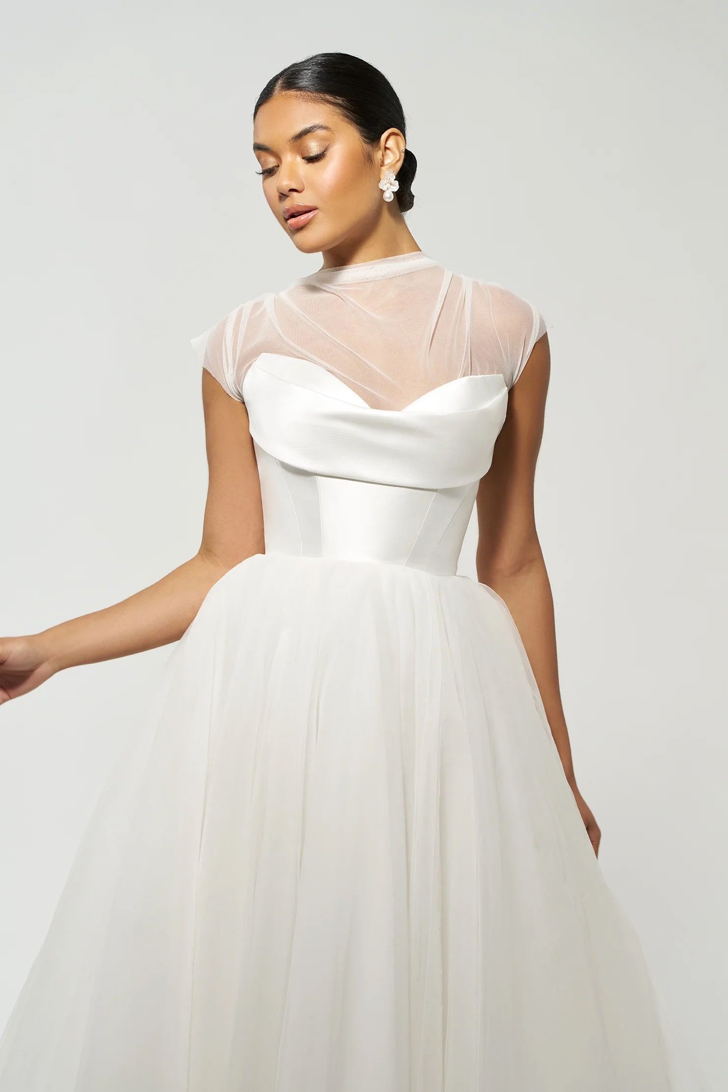 Woman in a white wedding dress with a high-neck lace top and a tulle skirt.