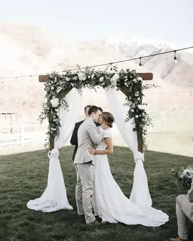Woman in wedding dress leans on a vintage van. Dress is white and flowing, with a high neckline.