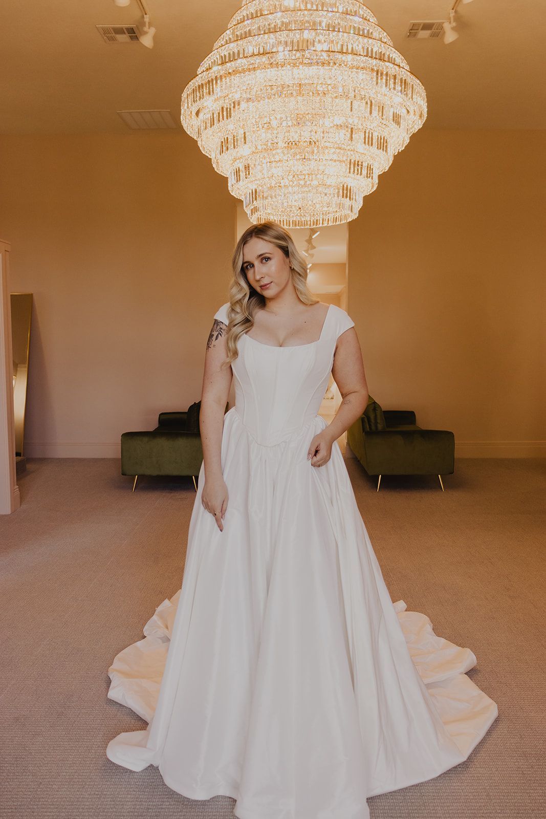 Woman in wedding dress poses in bridal shop.