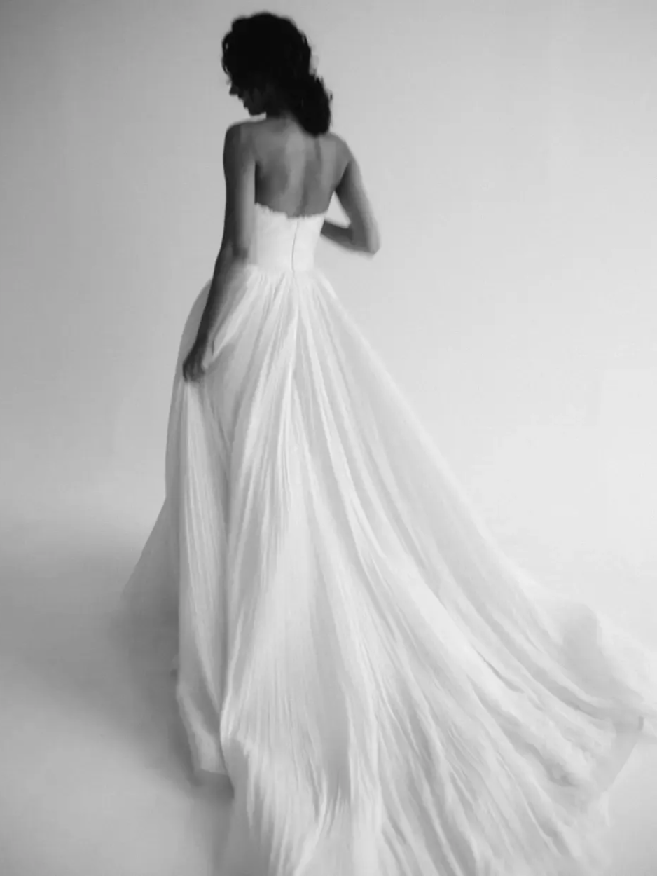 Woman in a white strapless gown, back to the camera, with a flowing train.