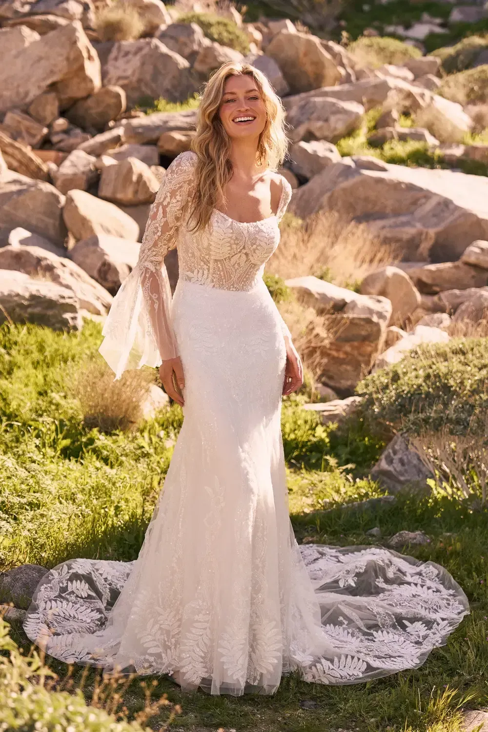 Woman in white wedding dress smiles outdoors.